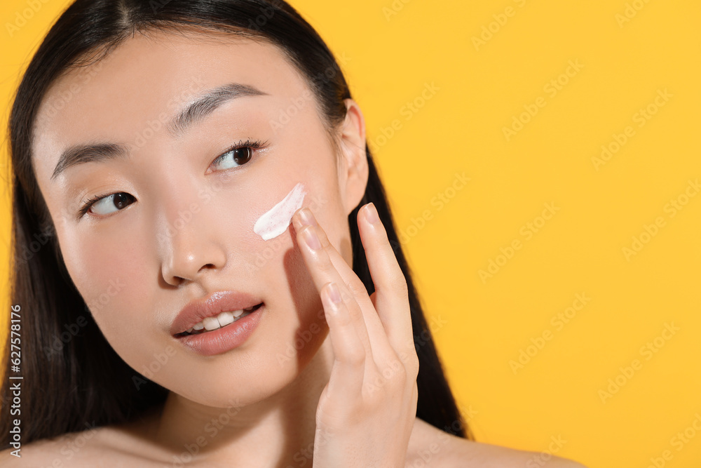 Beautiful young woman with sun protection cream on her face against orange background, closeup. Space for text Beautiful young woman with sun protection cream on her face against orange background, closeup. Space for text