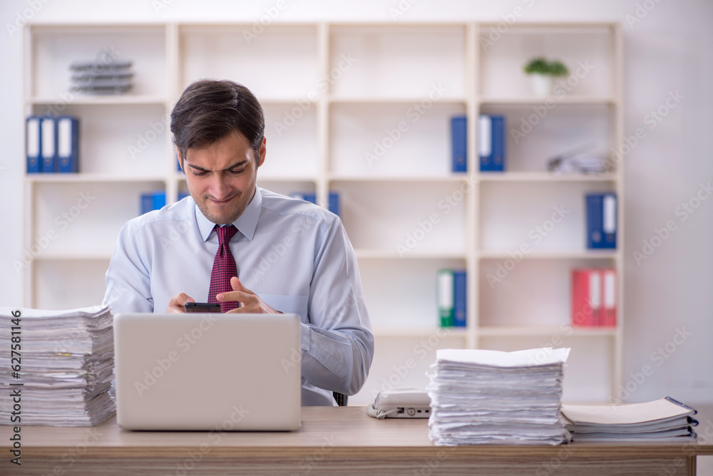 Young male employee and too much work in the office Young male employee and too much work in the office