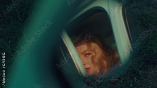 A long-haired blonde is reflected in a retro car mirror photo