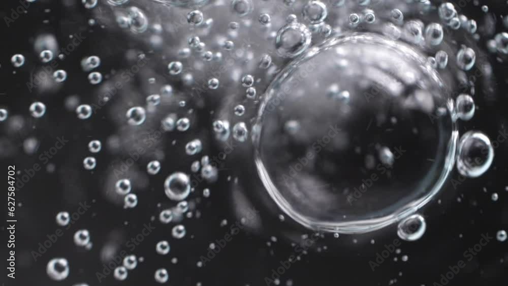 Slow motion speed closeup scene on small bubble joint together to be a bigger one isolated on black background, fizz texture of soda water drink when gas release, low surface tension condition