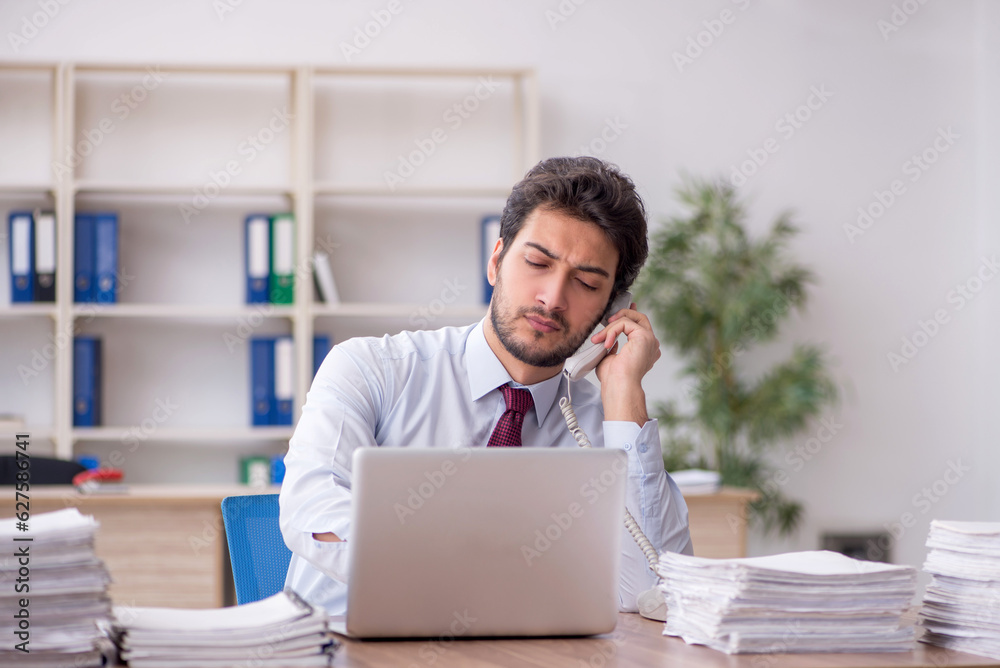 Young male employee and too much work in the office Young male employee and too much work in the office