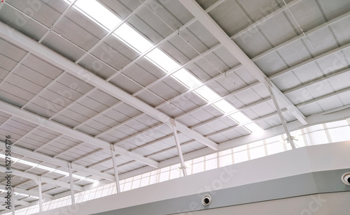 White steel roof and mesh ceiling grille with lay light inside of large modern building, low angle and perspective side view