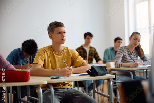 Teenage boy takes notes during class at high school.