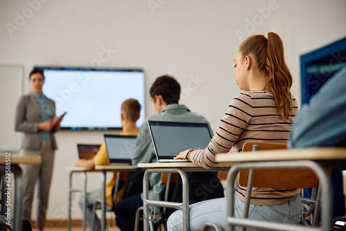 High school student and her classmates attending computer class in classroom.