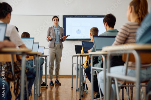 Female professor talks to her students during IT class at high school.