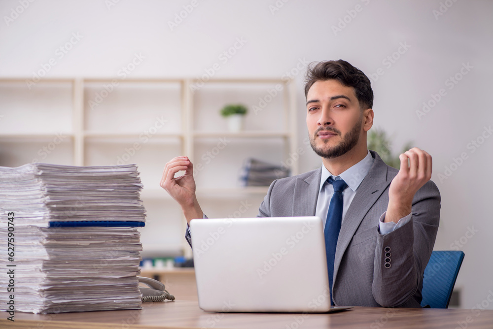 Young male employee and too much work in the office Young male employee and too much work in the office