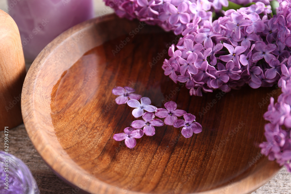 Bowl of water and lilac flowers on wooden table, closeup Bowl of water and lilac flowers on wooden table, closeup