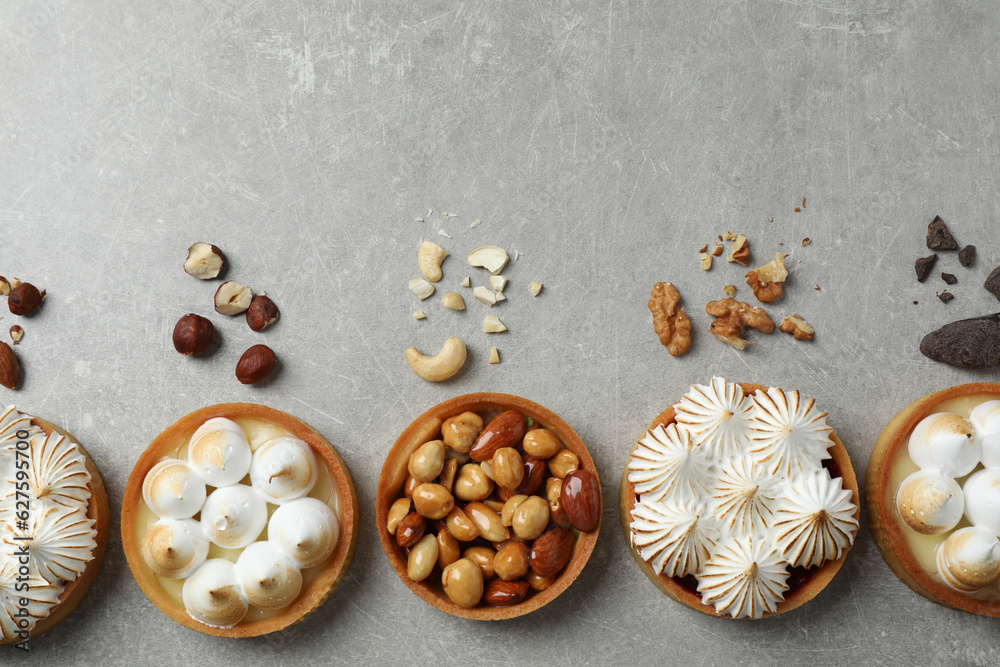 Many different tartlets on grey table, flat lay with space for text. Delicious dessert Many different tartlets on grey table, flat lay with space for text. Delicious dessert