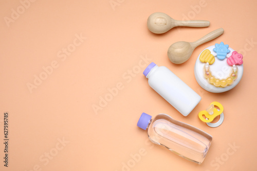 Flat lay composition with baby care products and accessories on pale orange background, space for text