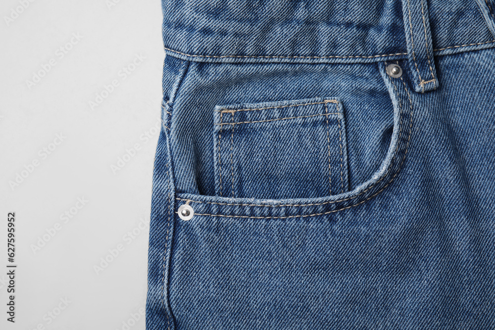 Jeans with pocket on light grey background, top view Jeans with pocket on light grey background, top view