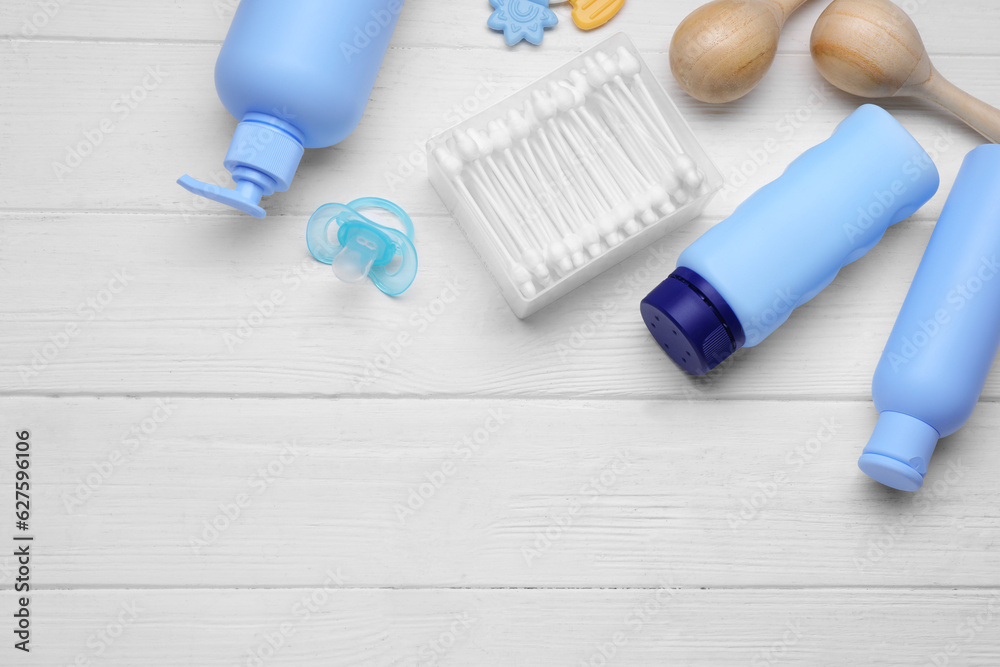 Naklejka premium Baby powder, shampoo, pacifier, cotton buds and toys on white wooden table, flat lay. Space for text