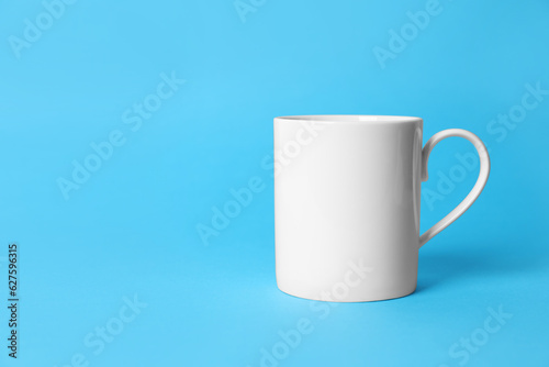 One white ceramic mug on light blue background. Space for text