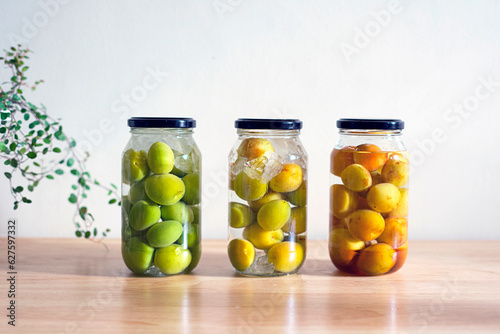 Umeshu, a Japanese liqueur made by steeping ume plums in liquor and sugar, on the table. 3 bottles of Umeshu.