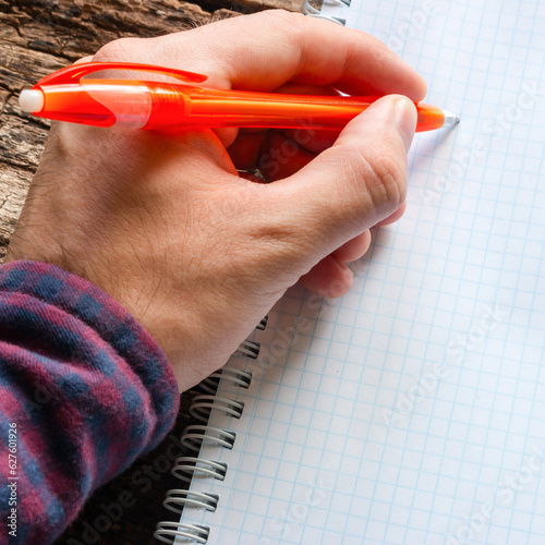 left-handed man writes in a notebook photo