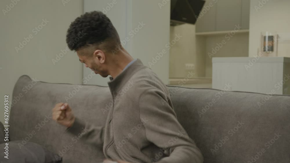 Man Winning Video Game Holding Joystick. 20s African American man playing video game sitting on couch at home. Happy with game victory. Man Winning Video Game Holding Joystick. 20s African American man playing video game sitting on couch at home. Happy with game victory.