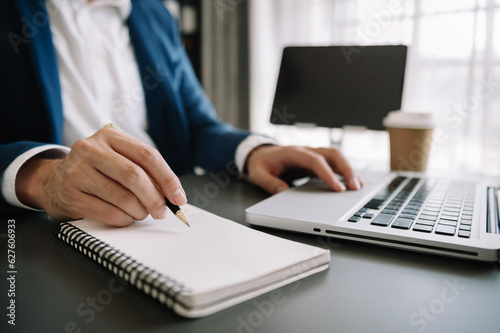 businesswoman hand working with new modern computer and writing on the notepad strategy diagram as concept morning light..