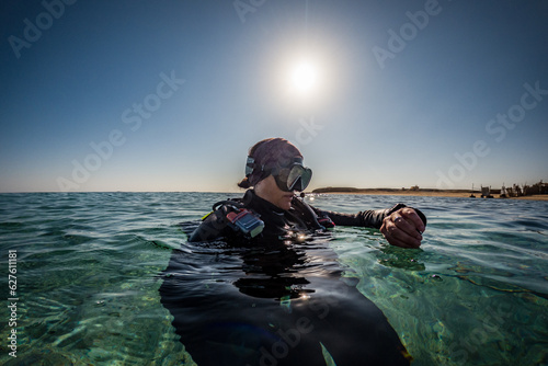 Scuba Diver checking Dive Computer on the Surface © feel4nature