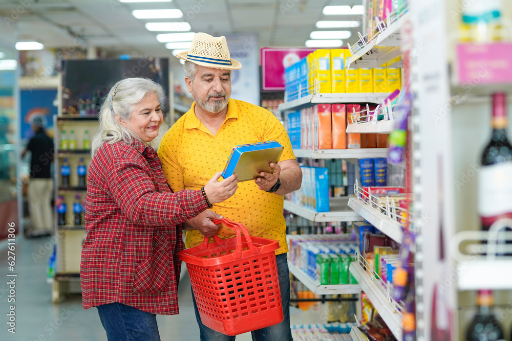 Senior indian couple looking product detail and purchasing together at grocery shop.