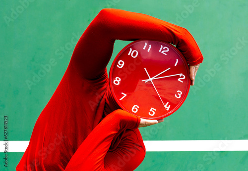 Anonymous person covering face with red clock photo