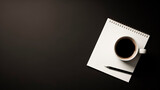 Coffee cup, pen and notepad on black background with copy space.