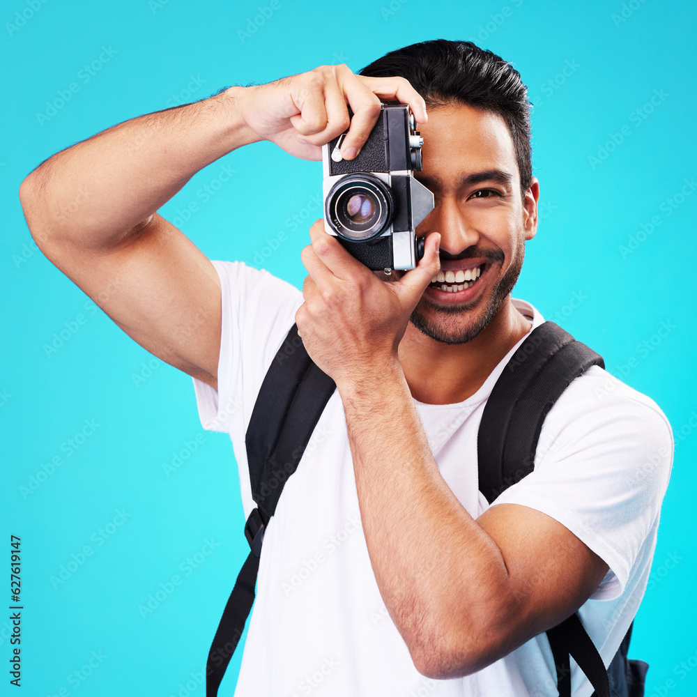 Portrait, smile and man with a camera, photography and taking picture against a blue studio background. Face, male person or model with creativity, vintage technology or photographer with inspiration