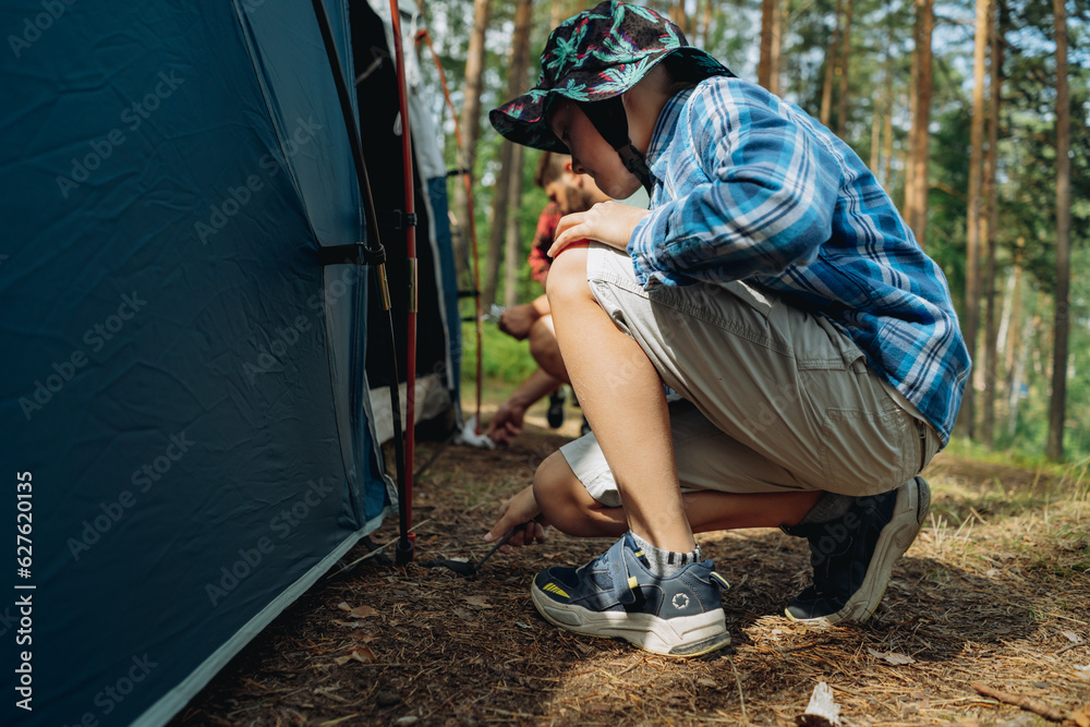 cute caucasian boy putting up a tent. Family camping concept