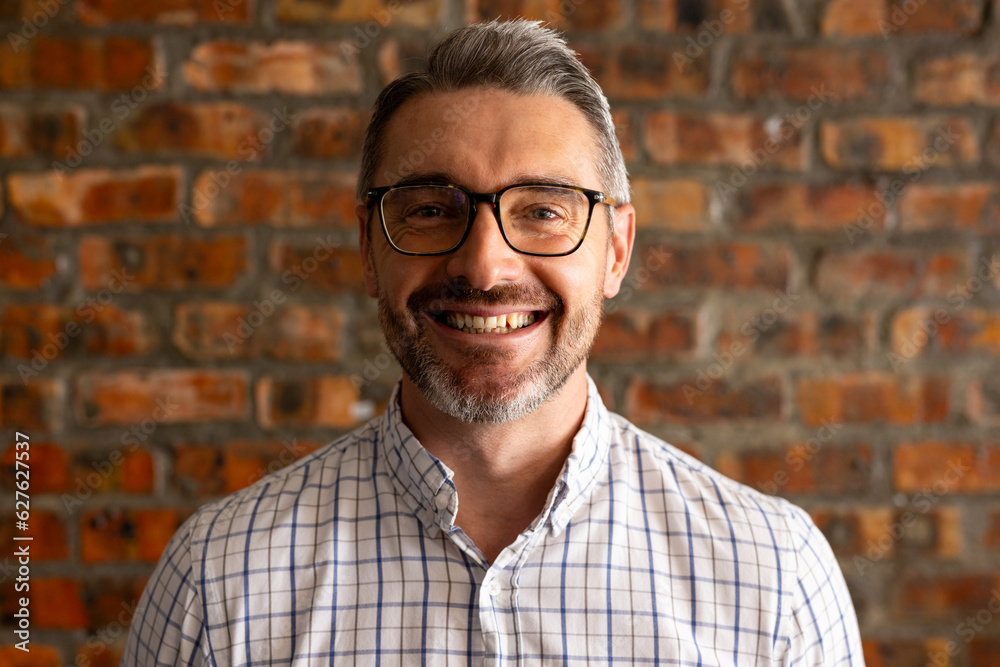 Portrait of a caucasian businessman smiling against brick wall at modern office Portrait of a caucasian businessman smiling against brick wall at modern office