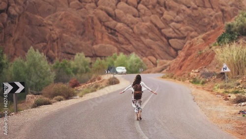 A young adventerous woman walking down the bendy road in the death valley in america on the hottest day of the year.