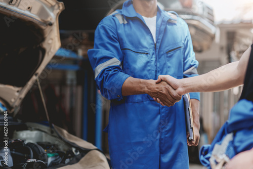 Auto mechanic handshake successful colleague in auto service center To congratulate the success of car maintenance. Professional car mechanic shaking hands.