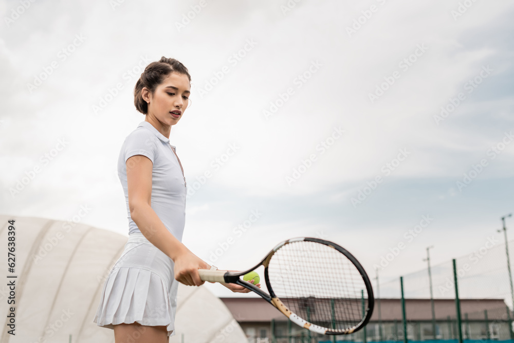 Fototapeta premium sportswoman holding tennis racket on court, active wear, athletic and sporty, motivation, health