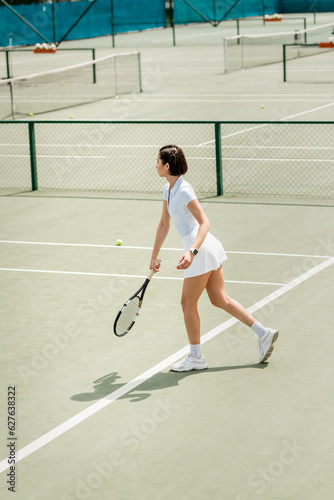 side view, sportswoman in white active wear holding racket on tennis court,  female player © LIGHTFIELD STUDIOS
