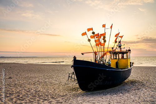 Fototapeta Naklejka Na Ścianę i Meble -  Sunset on the beach on the Polish Baltic Sea. Fishing boat in the evening near Międzyzdroje, Poland.
