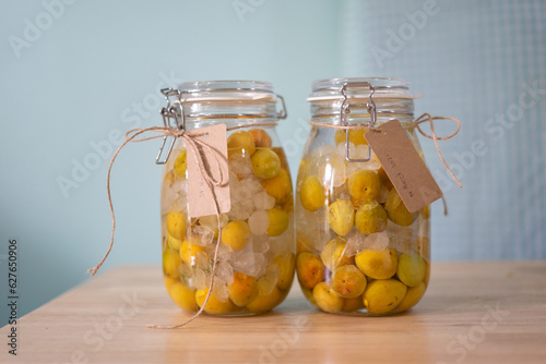 Umeshu, a Japanese liqueur made by steeping ume plums in liquor and sugar, on the table. 2 bottles of Umeshu. Umeshu with yellow plums.