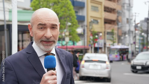 A Caucasian male reporter broadcasting on television in a local city. photo