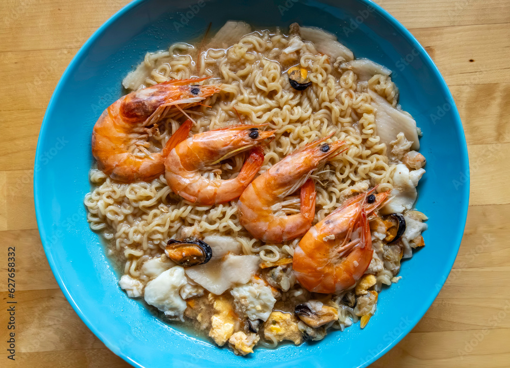 Instant noodles soup with shrimp, clam, and scrambled boiled eggs. Top view or flat lay.
