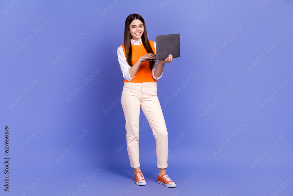 Full body length photo of schoolgirl chatting holding netbook remote part time education program isolated on violet color background Full body length photo of schoolgirl chatting holding netbook remote part time education program isolated on violet color background