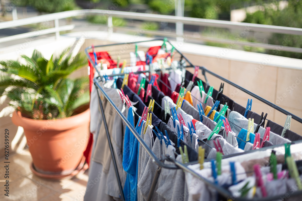 Colorful clean laundry hanging on clothesline, selective focus. Laundry is attached to the hanger with clothespin. Routine housework, hygiene, cleaning concept.