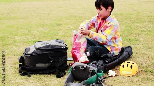   Cheerful child of elementary age sitting in park eating bread while using phone photo