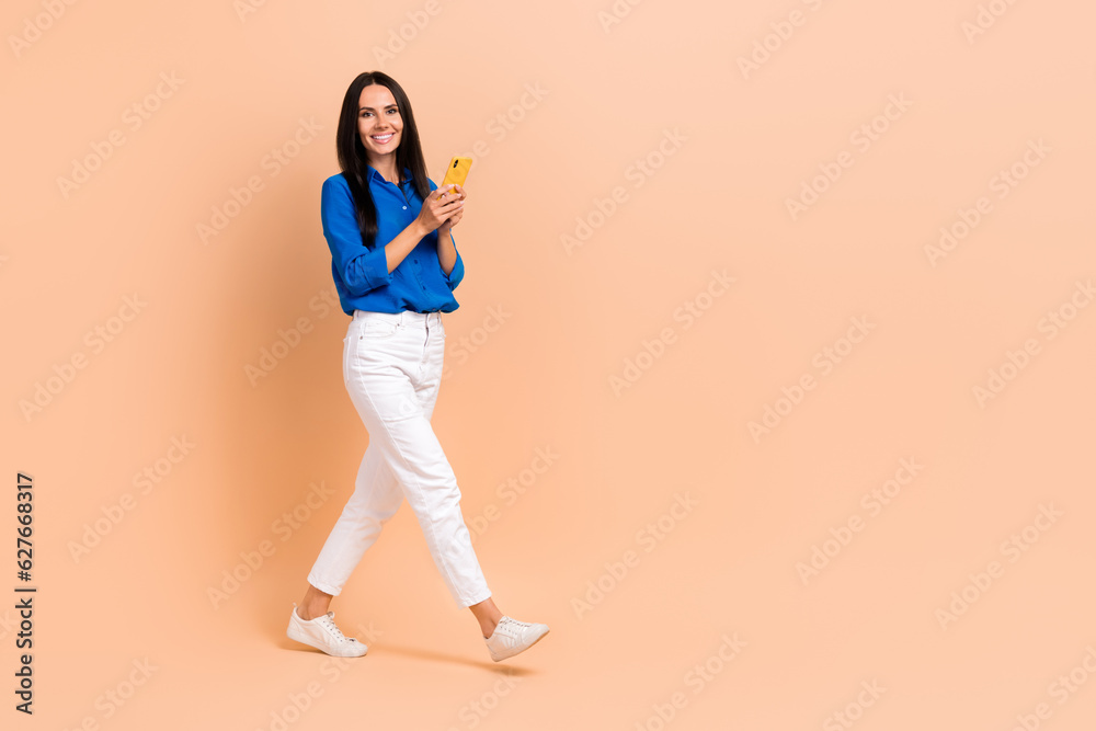 Full length profile side photo of cheerful adorable lady wear blue stylish clothes going empty space isolated on beige color background Full length profile side photo of cheerful adorable lady wear blue stylish clothes going empty space isolated on beige color background