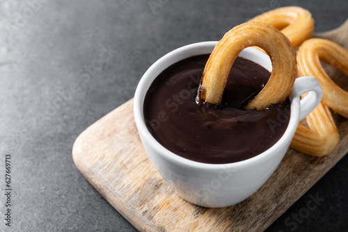 Traditional Spanish churros with hot chocolate on black slate background
