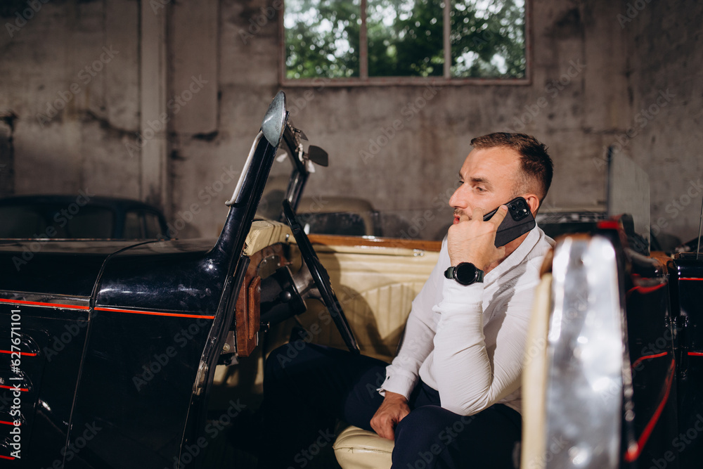 a man is talking on the phone while sitting in a retro cabriolet a man is talking on the phone while sitting in a retro cabriolet