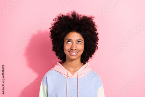 Portrait of cute positive schoolkid beaming smile look up above empty space advert isolated on pink color background