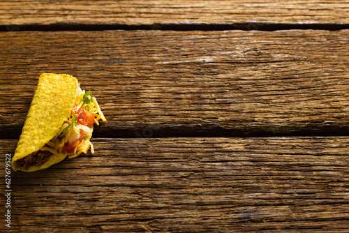 High angle view of taco filled with cheese and meat over wooden table