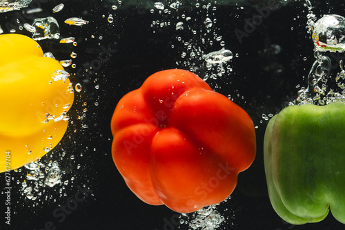 Close up of peppers falling into water with copy space on black background