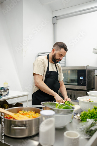 Young chef cutting peppers