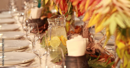 A close-up shot of a table set in an autumn style. Table setting-decoration of a large table with leaves on an autumn theme for receiving guests.
