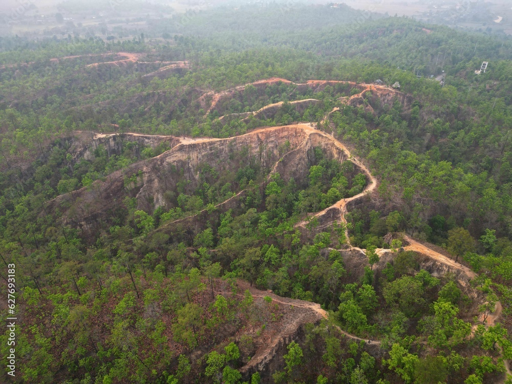 The epic, smoggy Pai Canyon in Pai, Thailand taken from above from a bird's eye view with the drone surrounded by trees.