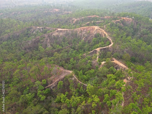 The epic, smoggy Pai Canyon in Pai, Thailand taken from above from a bird's eye view with the drone surrounded by trees.