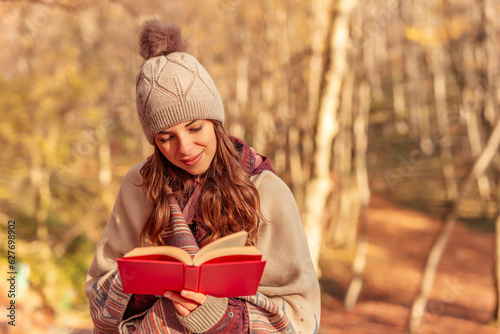 Woman reading a book on sunny autumn day outdoors