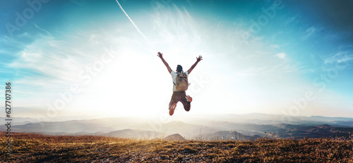 Fotografia Happy man with arms up jumping on the top of the mountain - Successful hiker cel